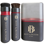 Buff & Bloom haircare set featuring a black cylindrical brush with soft bristles, a matching black cylindrical bottle with red liquid and bristles, and a large rectangular box with a translucent lid and gold logo, all on a white background.