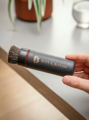 buff & Bloom horsehair brush held by a hand